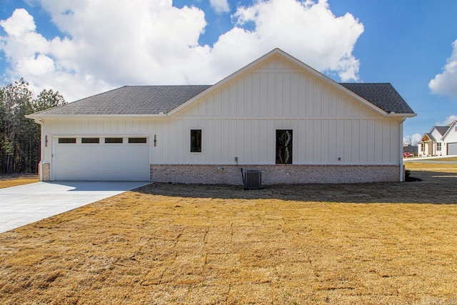 exterior space featuring a shingled roof, concrete driveway, an attached garage, a yard, and brick siding