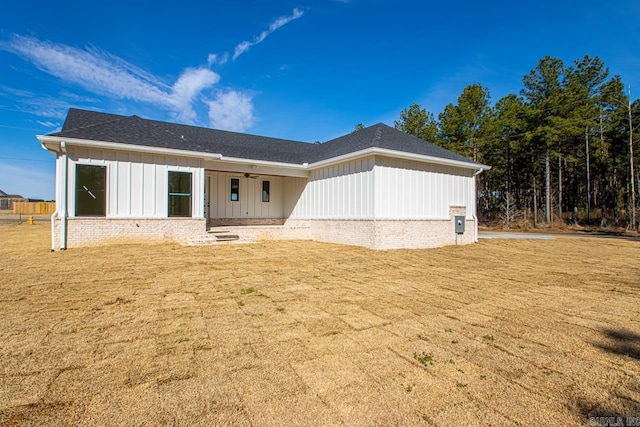 view of front of house with a front lawn, board and batten siding, and roof with shingles