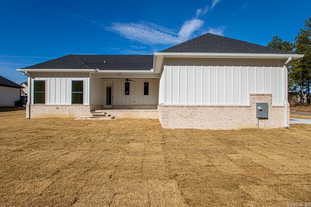 rear view of property with a yard, a shingled roof, board and batten siding, and a ceiling fan