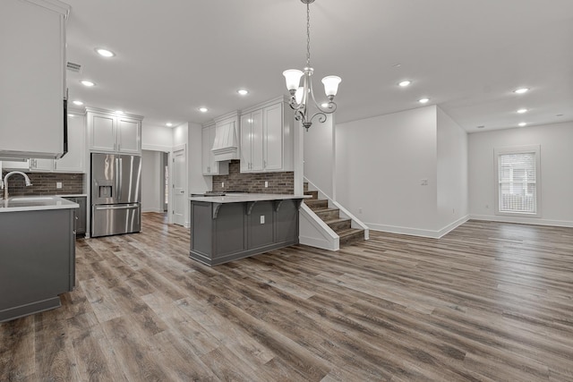 kitchen featuring recessed lighting, a peninsula, wood finished floors, light countertops, and stainless steel fridge