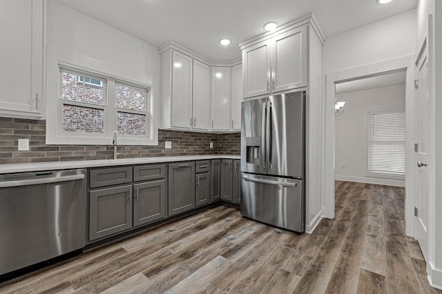 kitchen with backsplash, stainless steel appliances, dark wood-type flooring, and gray cabinetry