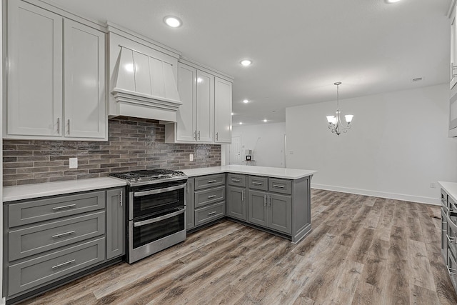 kitchen featuring range with two ovens, light wood-style flooring, gray cabinetry, light countertops, and decorative backsplash