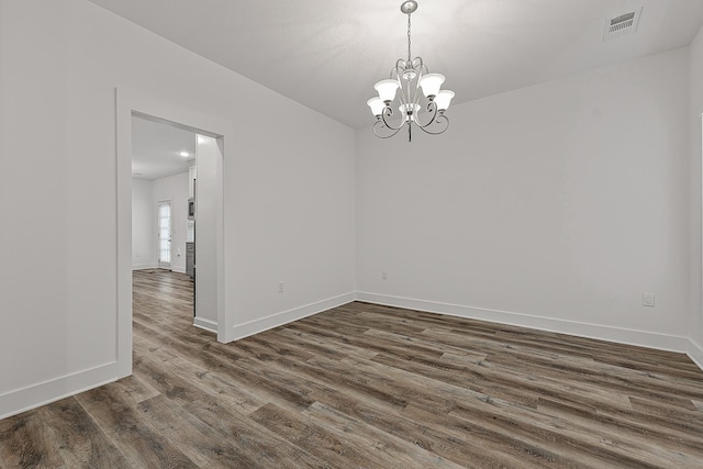 spare room featuring an inviting chandelier, baseboards, visible vents, and dark wood-style flooring