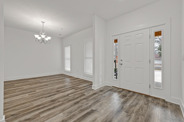 foyer with baseboards, wood finished floors, and an inviting chandelier