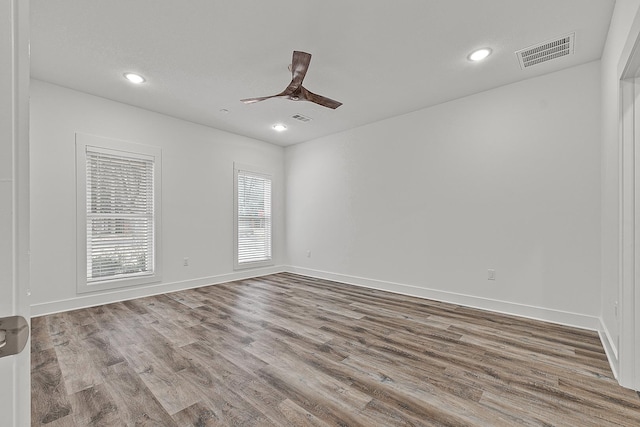 unfurnished room with a ceiling fan, visible vents, baseboards, and wood finished floors