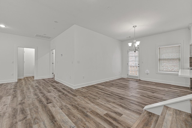 interior space featuring baseboards, visible vents, an inviting chandelier, and wood finished floors