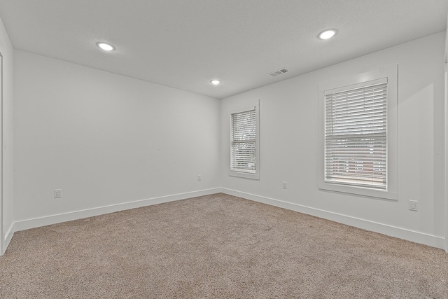 empty room featuring carpet, visible vents, baseboards, and recessed lighting