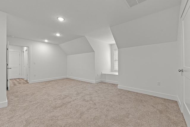 additional living space featuring carpet floors, visible vents, vaulted ceiling, and baseboards