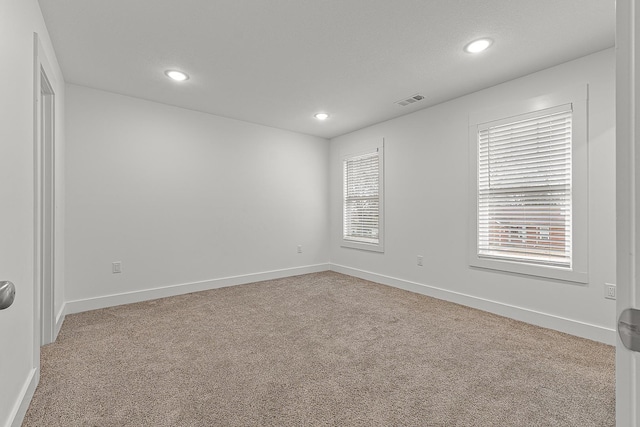 spare room with carpet floors, recessed lighting, visible vents, and baseboards