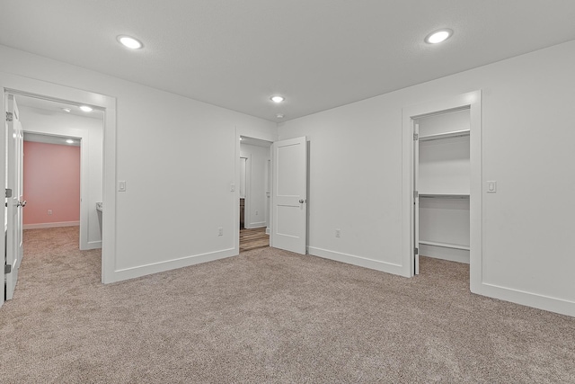 unfurnished bedroom featuring carpet flooring, a spacious closet, and baseboards