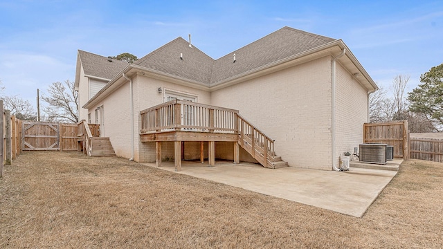 rear view of house featuring a deck, a patio, a fenced backyard, brick siding, and a gate