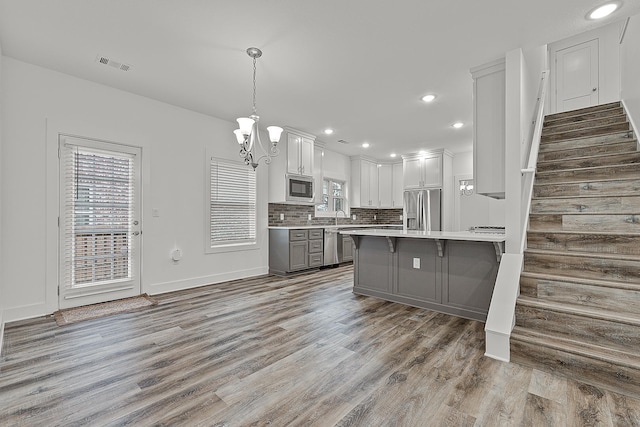 kitchen with gray cabinetry, stainless steel appliances, visible vents, light countertops, and tasteful backsplash