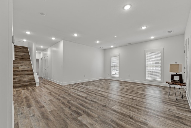 unfurnished living room with recessed lighting, wood finished floors, and stairs