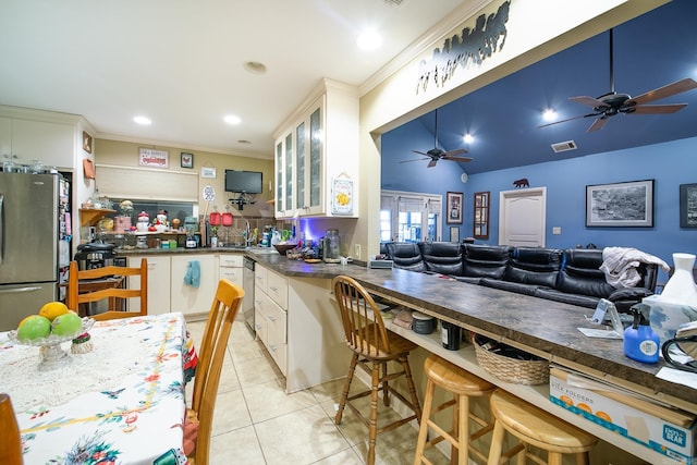 kitchen featuring light tile patterned floors, visible vents, dark countertops, glass insert cabinets, and stainless steel appliances