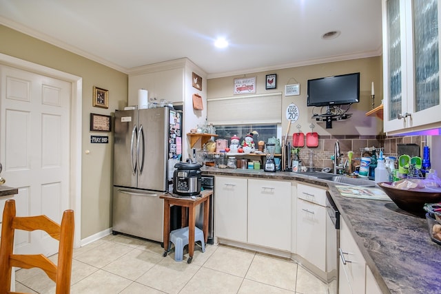 kitchen featuring light tile patterned floors, a sink, ornamental molding, appliances with stainless steel finishes, and dark countertops