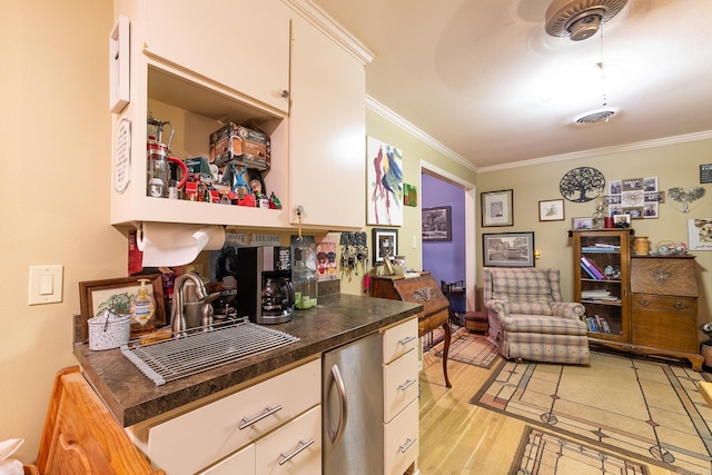 kitchen with light wood-style floors, visible vents, a sink, and ornamental molding