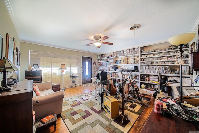 interior space with ceiling fan, visible vents, crown molding, and wood finished floors