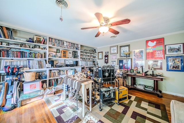 office space featuring baseboards, visible vents, ceiling fan, wood finished floors, and crown molding