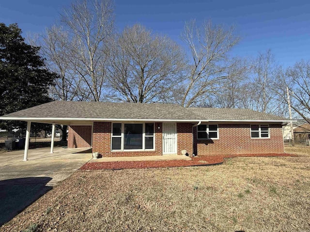 ranch-style home with brick siding, roof with shingles, an attached carport, driveway, and a front lawn