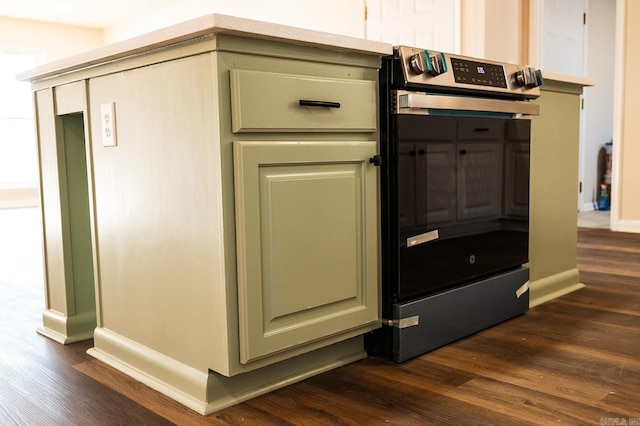 interior details with dark wood-style flooring, baseboards, green cabinetry, and stainless steel electric range