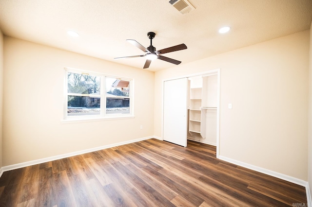 unfurnished bedroom featuring dark wood-style floors, a closet, visible vents, and baseboards