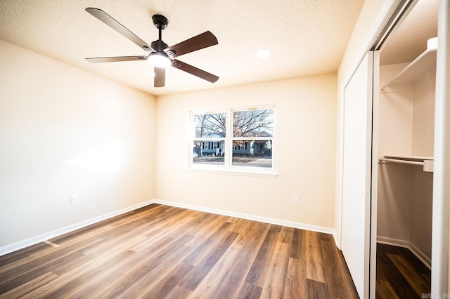 unfurnished bedroom featuring a textured ceiling, a closet, wood finished floors, and baseboards