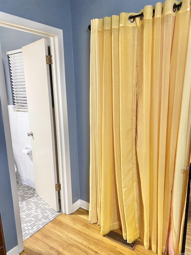 bathroom featuring tile walls, wood finished floors, and visible vents