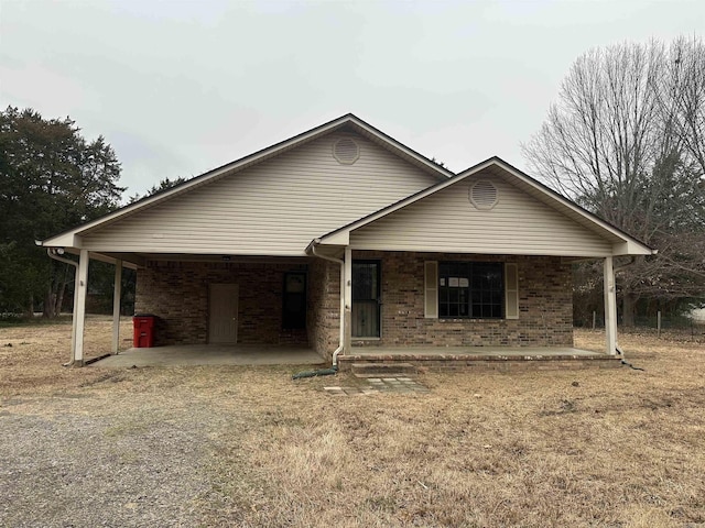 ranch-style house with driveway, brick siding, and a porch