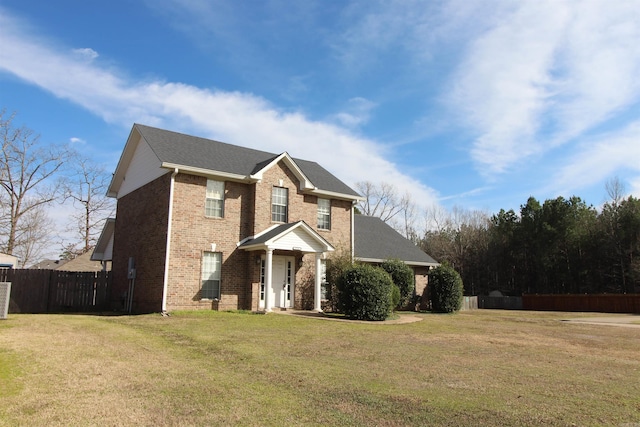 traditional-style house with fence, a front lawn, and brick siding