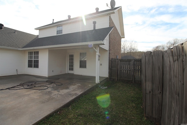 rear view of house featuring a patio area, a shingled roof, and fence