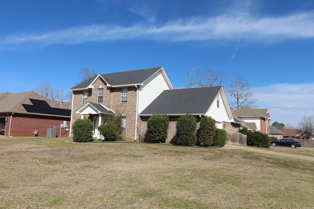 traditional home featuring brick siding, a front yard, and fence