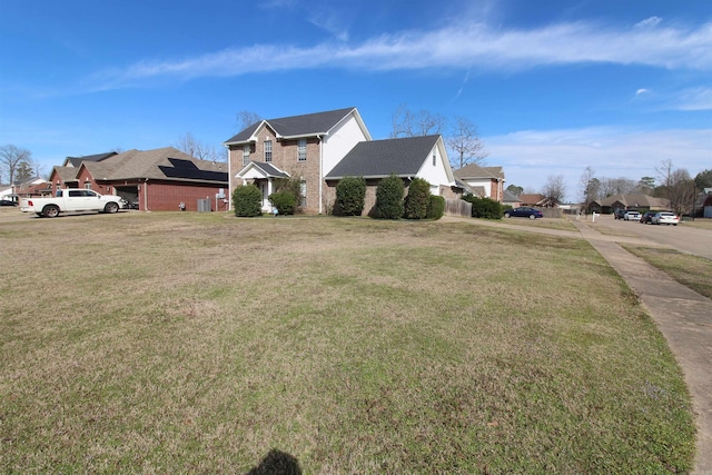 exterior space featuring brick siding, a residential view, and a front yard