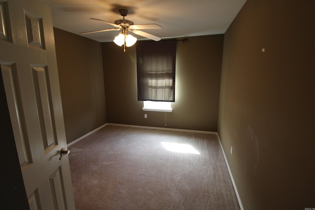 carpeted spare room featuring a ceiling fan and baseboards