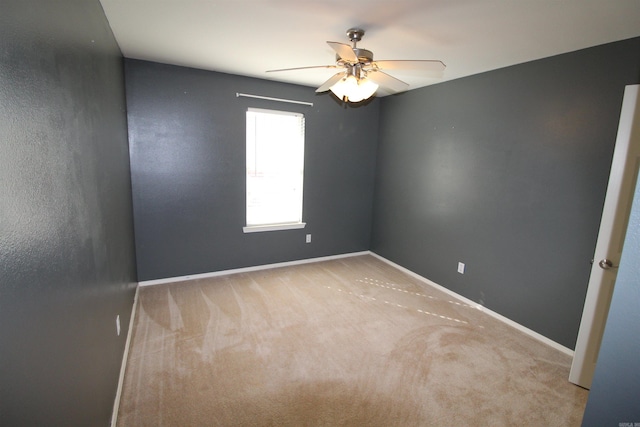 carpeted spare room featuring a ceiling fan and baseboards