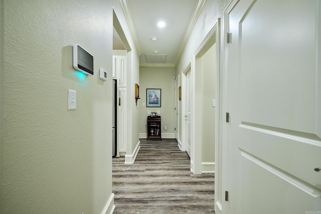 corridor featuring a textured wall, crown molding, baseboards, and wood finished floors