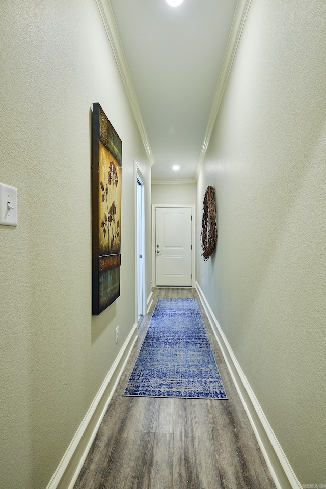 corridor with ornamental molding, baseboards, and wood finished floors