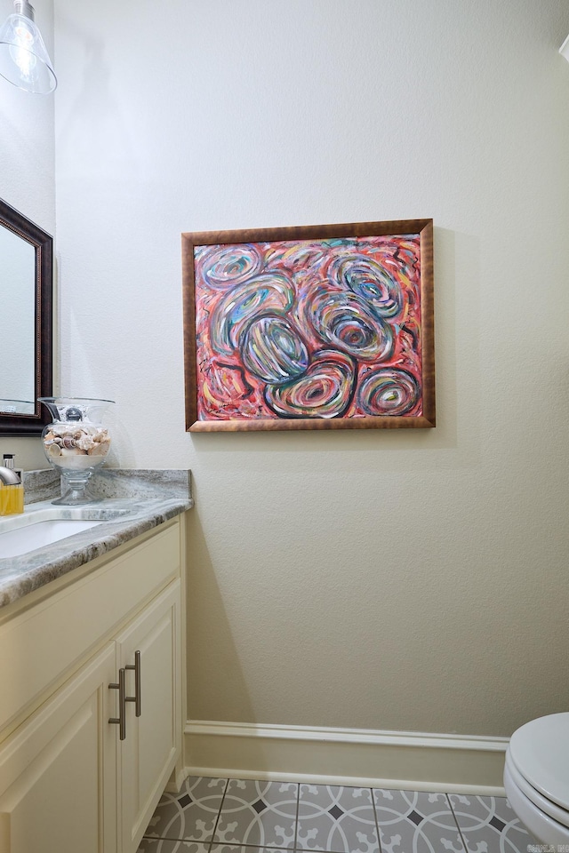 bathroom featuring toilet, tile patterned flooring, vanity, and baseboards