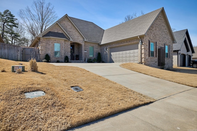 french country style house with driveway, brick siding, an attached garage, and fence