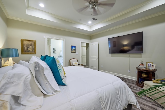 bedroom featuring visible vents, a raised ceiling, crown molding, and wood finished floors