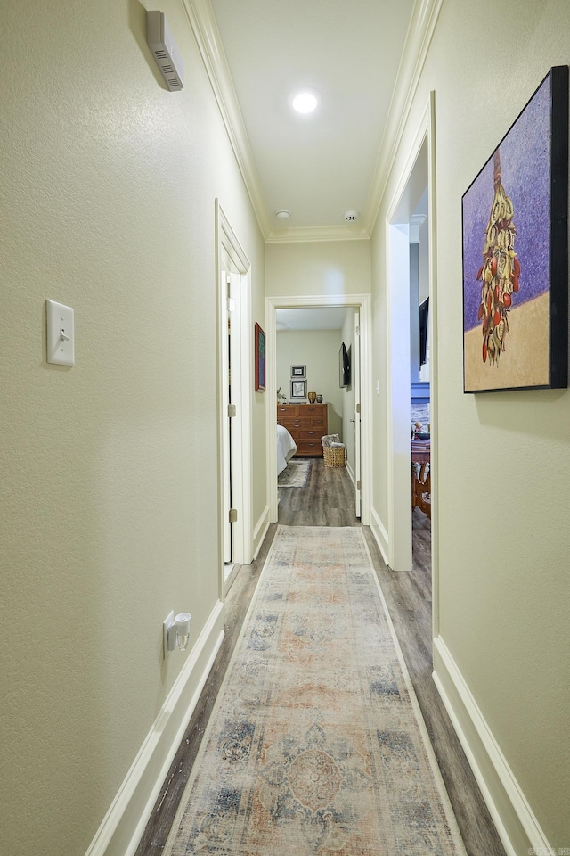 corridor featuring baseboards, ornamental molding, and wood finished floors