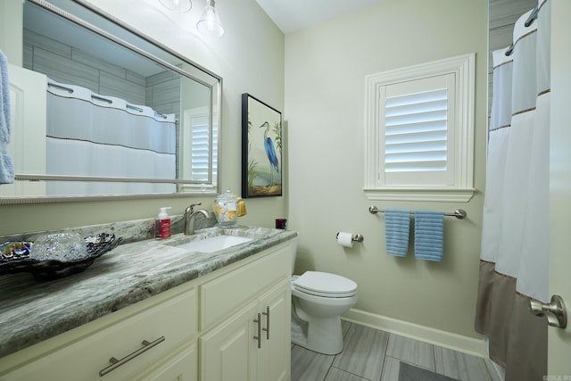 bathroom featuring toilet, vanity, and baseboards