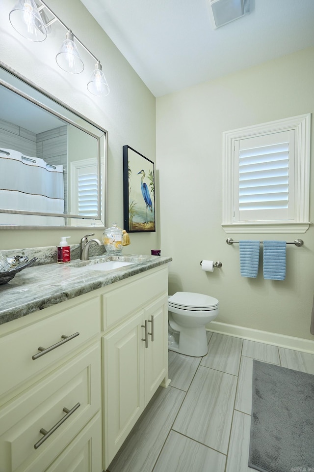 bathroom featuring toilet, visible vents, vanity, baseboards, and a shower with curtain