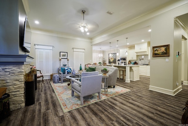 living area with crown molding, dark wood finished floors, visible vents, ceiling fan, and baseboards