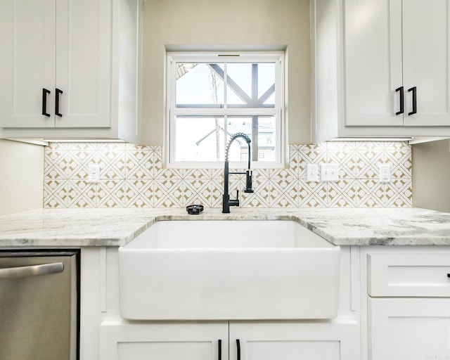 kitchen featuring stainless steel dishwasher, decorative backsplash, a sink, and light stone countertops