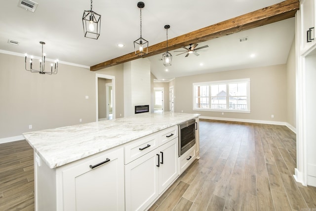 kitchen with visible vents, baseboards, open floor plan, light wood-style floors, and stainless steel microwave