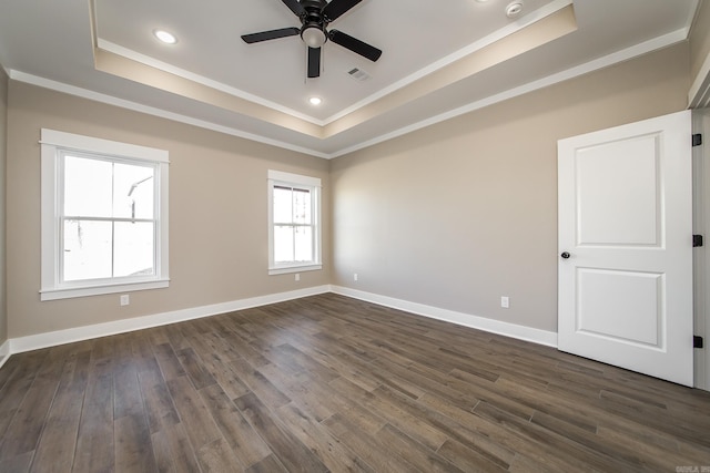 empty room with dark wood-style floors, ornamental molding, a raised ceiling, and baseboards