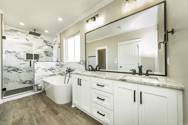 full bath with a marble finish shower, a soaking tub, ornamental molding, wood finished floors, and a sink