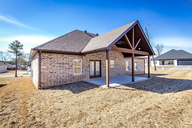 rear view of property featuring a shingled roof, a ceiling fan, a patio, french doors, and brick siding