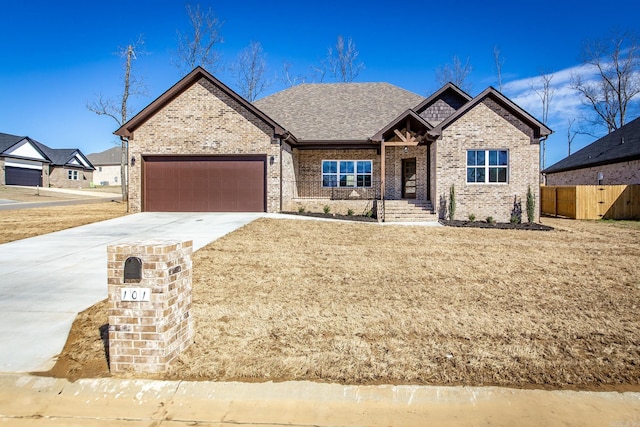 view of front facade featuring driveway, brick siding, an attached garage, and fence