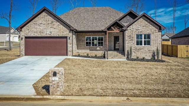 view of front of house with brick siding, driveway, an attached garage, and fence